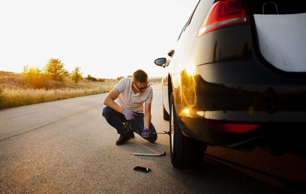 selladores de neumaticos - coche-pinchado-joven-cambiando-rueda